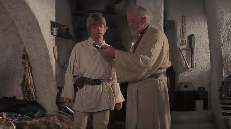 Obi-Wan Kenobi giving Luke Skywalker a lightsaber in Star Wars Episode IV A New Hope.