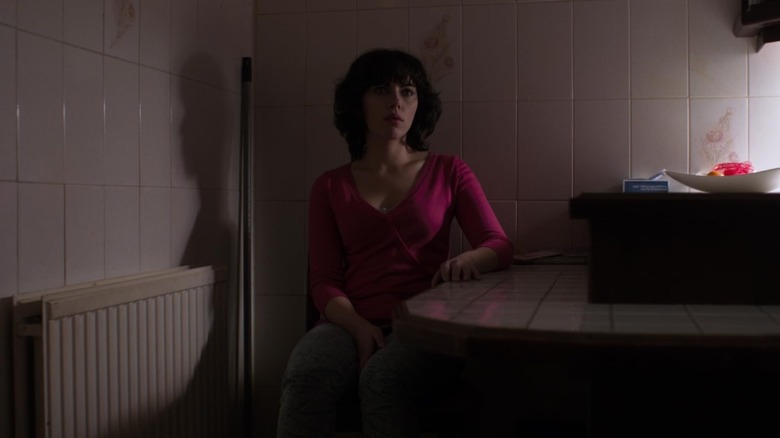 The Female (Scarlet Johansson) sat at a kitchen table in Under the Skin