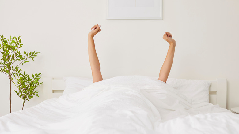 A woman waking up in bed in the morning.