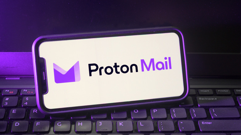 Proton Mail logo displayed on smartphone over keyboard.
