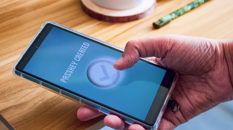 A person holding up a phone showing 'passkey created' on the screen