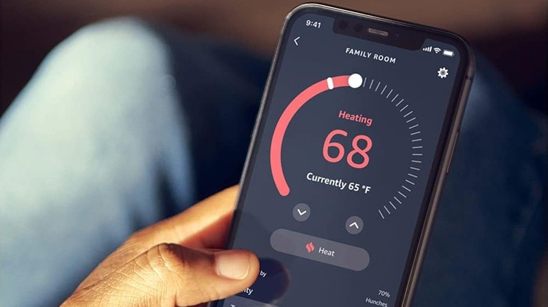 A person using the Alexa app to control a smart thermostat.