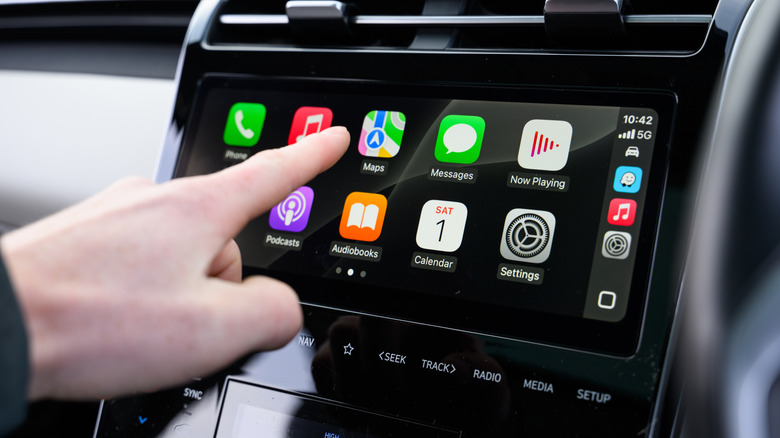 A hand interacting with Apple CarPlay screen inside a vehicle