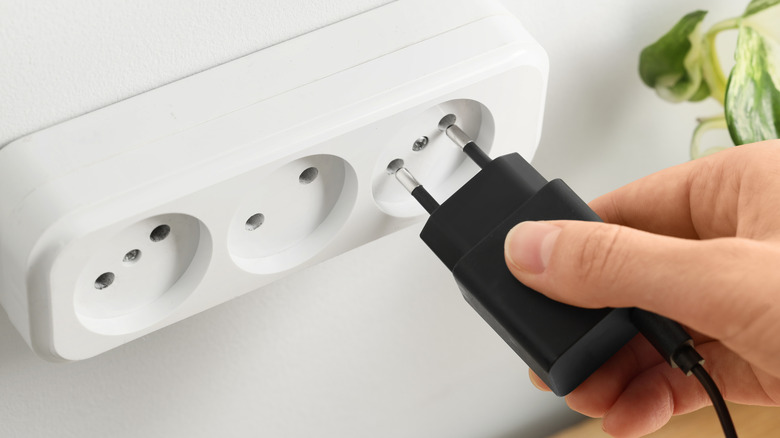 Close-up of a European smartphone charger and its plug going into a socket.