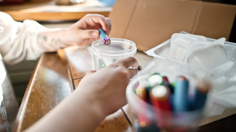 A woman sorting batteries into plastic cups.