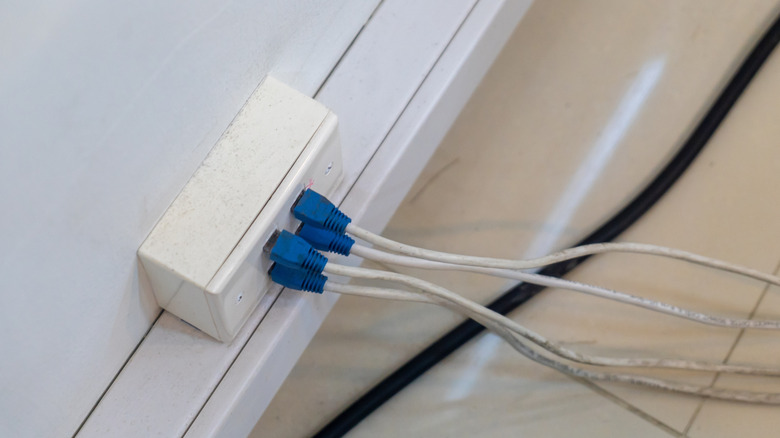 Person plugging in wired Ethernet cable into back of router.