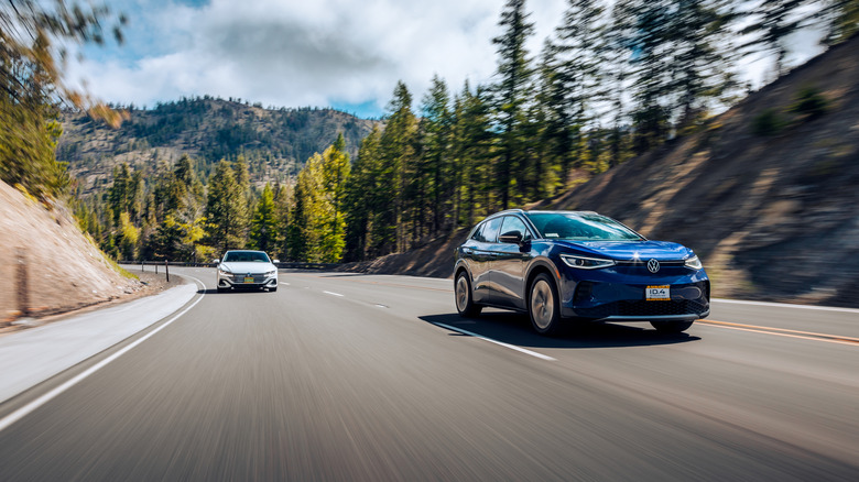 Two vehicles driving on a stretch of mountain road.
