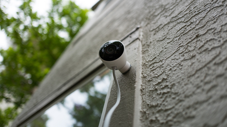 A Google Nest camera mounted to an exterior window frame.