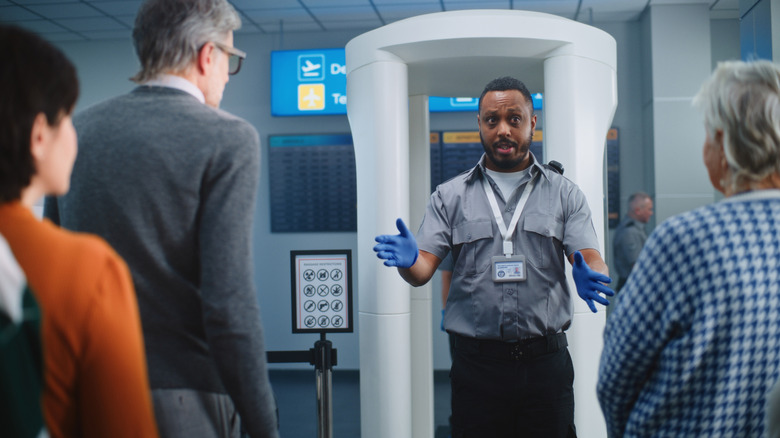 TSA security agent with line in front of metal scanner.