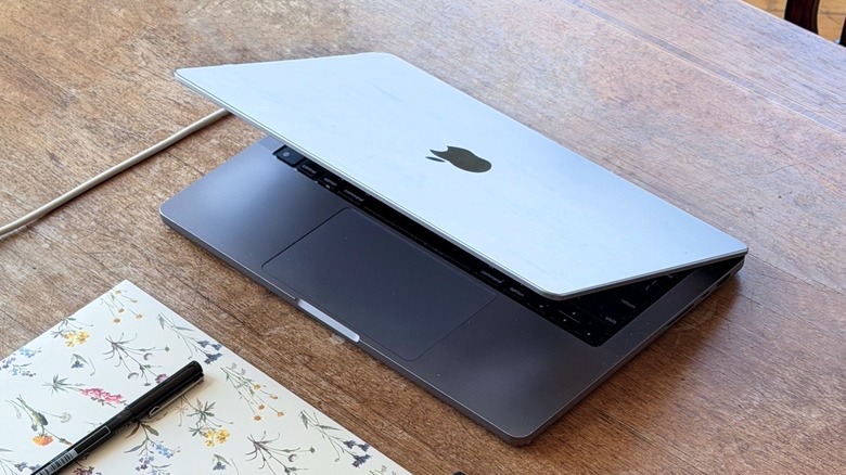 Half-closed MacBook on a wooden table