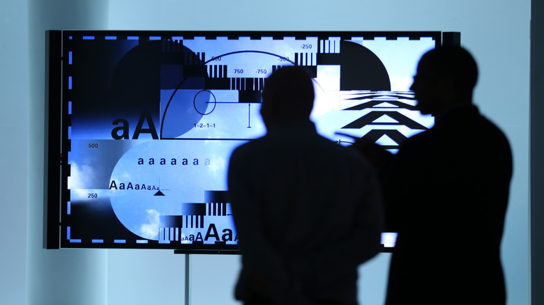 The silhouettes of two people looking at an OLED TV.