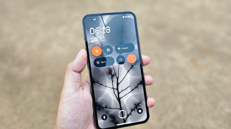 person holding a smartphone running nothing OS lock screen
