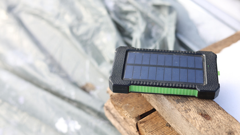 A portable solar power bank placed on a wooden structure under sunlight