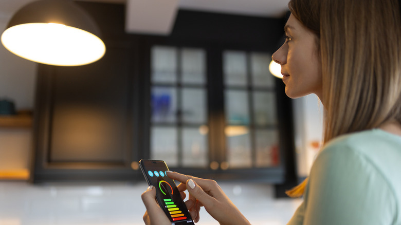 A person controlling a smart bulb using an app on their phone