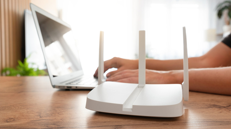 A person sitting next to a laptop near a white router
