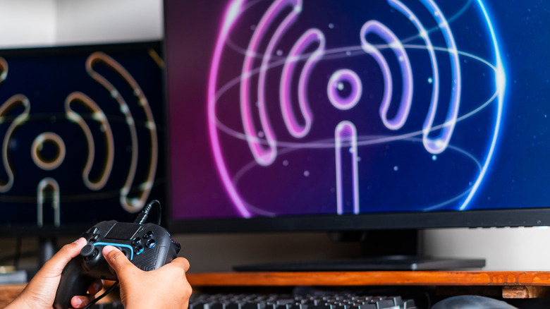 a person holding a controller by a monitor and keyboard showing a 3D Wi-Fi transmission symbol