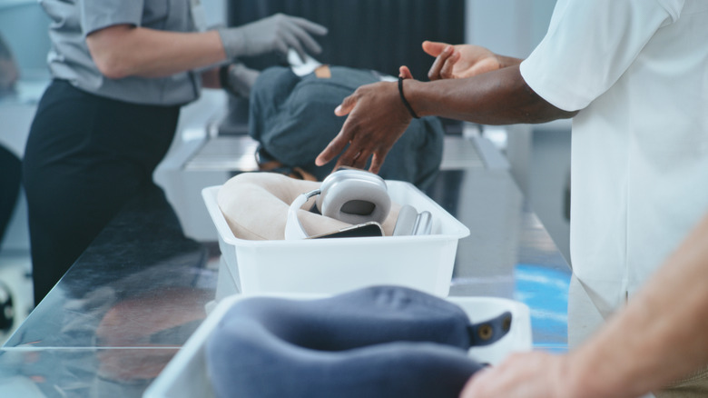 A person placing headphones and other belongings into a bin at a TSA checkpoint.
