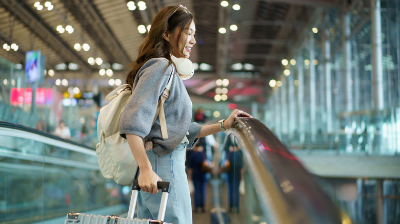 A person wearing headphones around the neck at an airport.