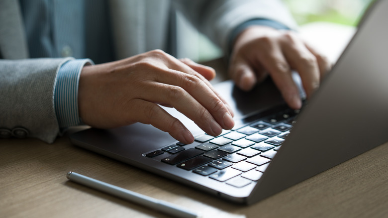 Close-up of hands of business professional using laptop