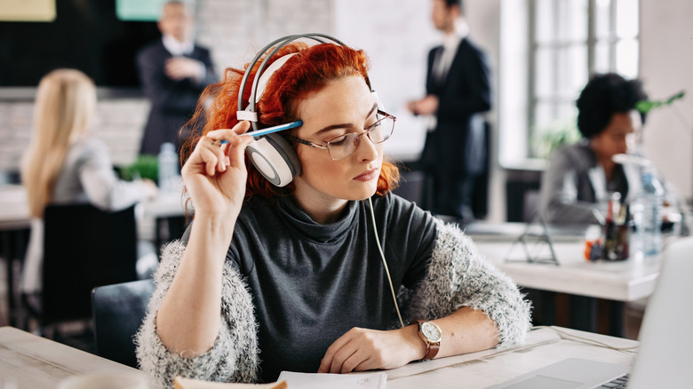 Person wearing headphones in a busy office