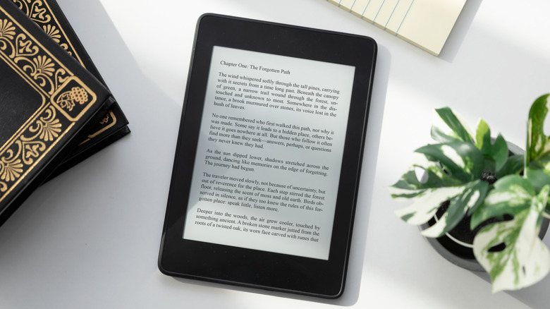 E-Reader displaying ebook page on desk next to books and plant