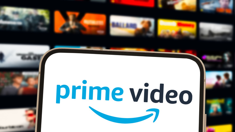 The Amazon Prime Video logo displayed on a smartphone screen. Movies and show options are the background.