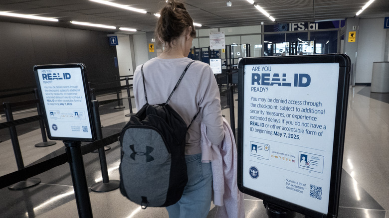 A woman walking through an airport with a RealID sign.