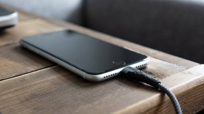 A phone plugged into a USB cable on a table