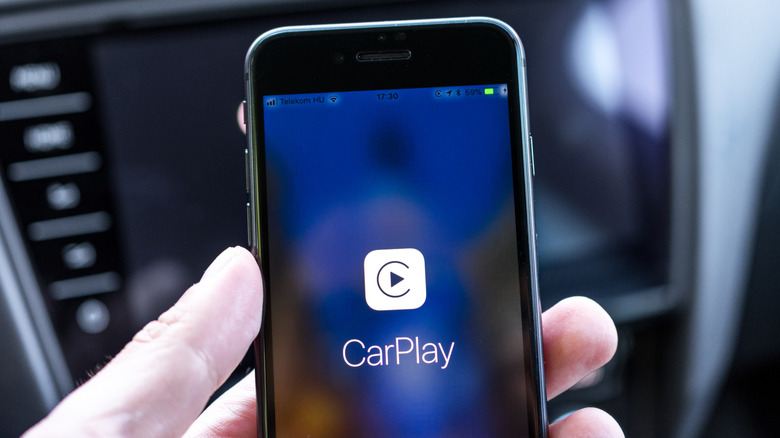 A person holding a phone with the CarPlay logo on its screen