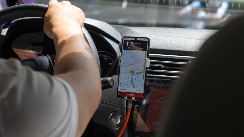 A Chinese rideshare driver uses the Dida Taxi app from his phone to provide transportation services in Shanghai, China.