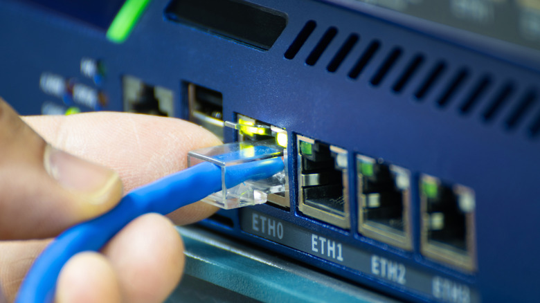 Person connecting an Ethernet cable to a modem.
