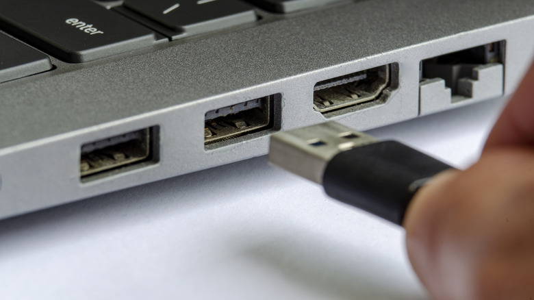 USB cord being plugged into a USB port on a laptop.