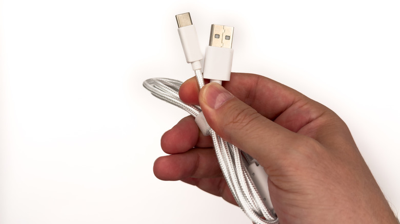 A hand holding USB Type-A and USB Type-C cables.