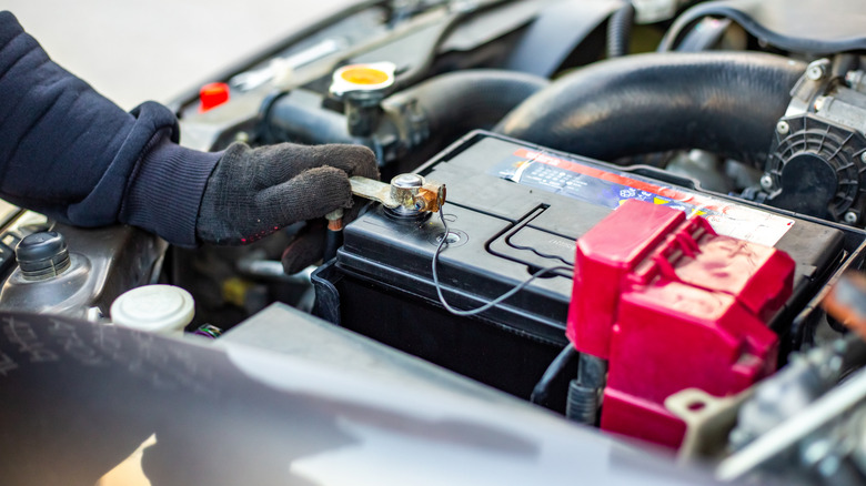 A mechanic works on a car battery.