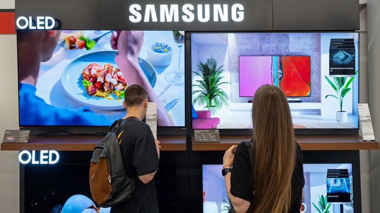 Two customers looking at Samsung storefront TVs