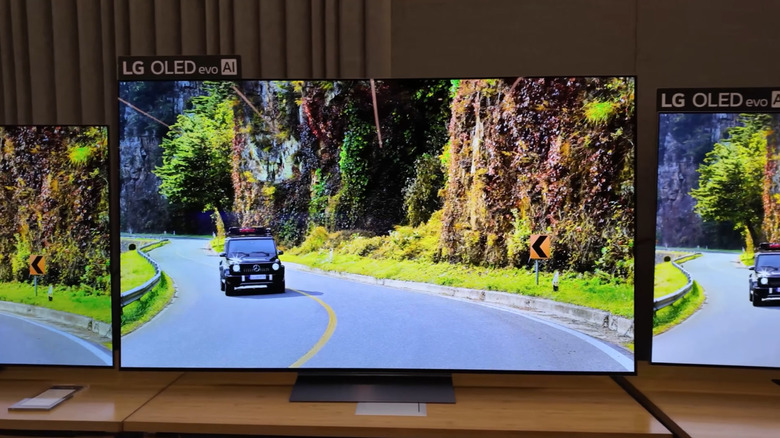 A lineup of LG OLED TVs showing a car driving down a road