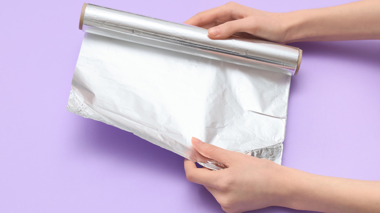 A person preparing a sheet of aluminum foil