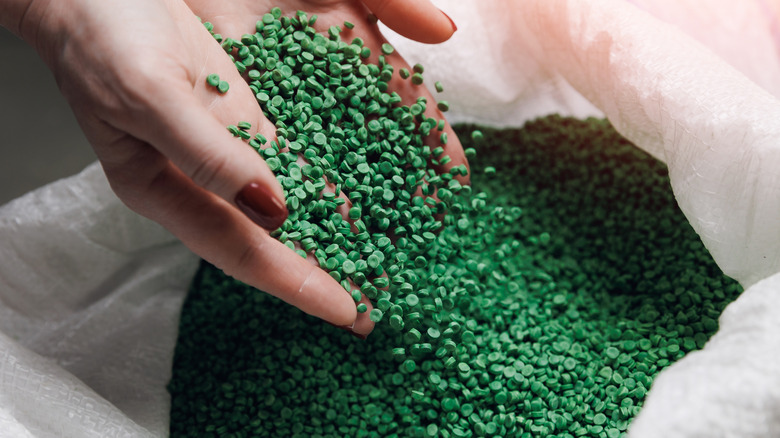 green plastic pellets dropped inside a white bag