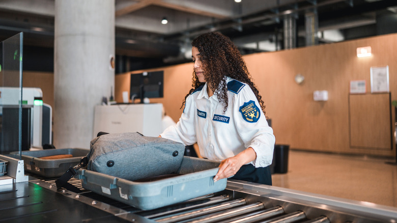 A TSA agent checks bins