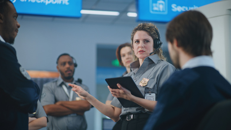 Security agent with tablet and having discussions at TSA checkpoint.