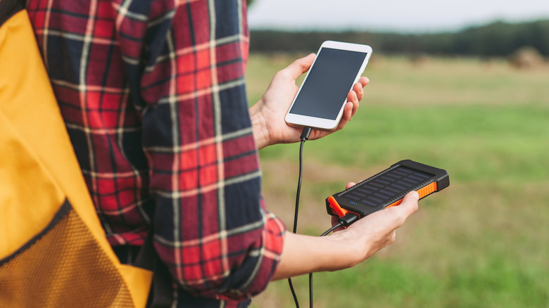 A person charging a smartphone using a portable power bank