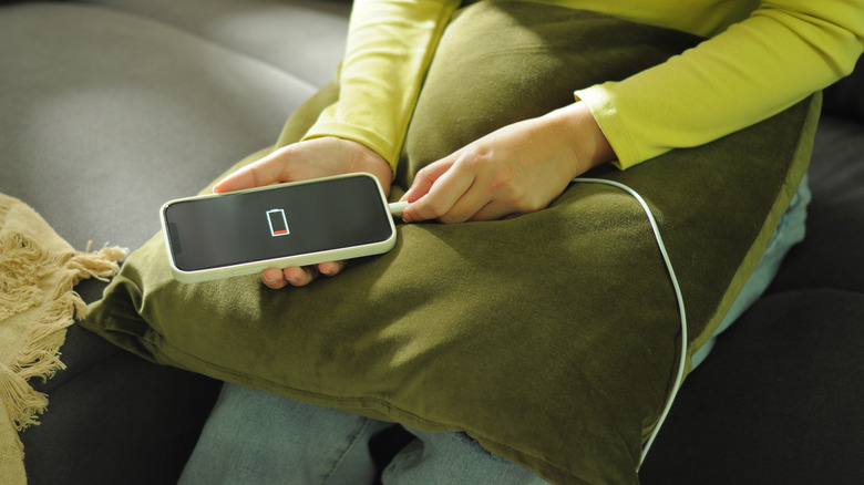 A person plugging in a phone showing a low battery warning