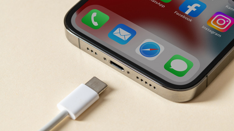 USB-C cable going into a USB-C port on an Apple iPhone model.