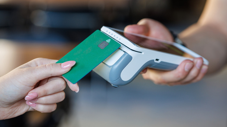 Person using a chip card to complete a purchase on a handheld scanner.