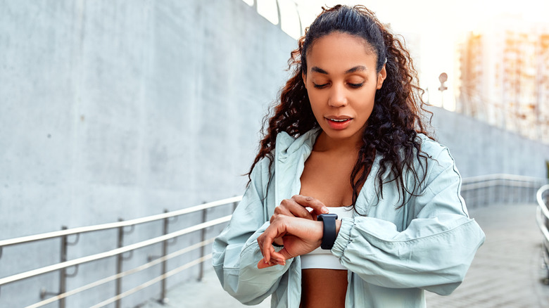 Woman looking at her smartwatch during an early day workout.