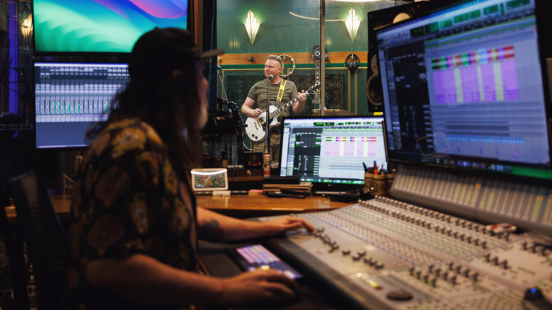 Musician recording a song in a studio with an audio engineer