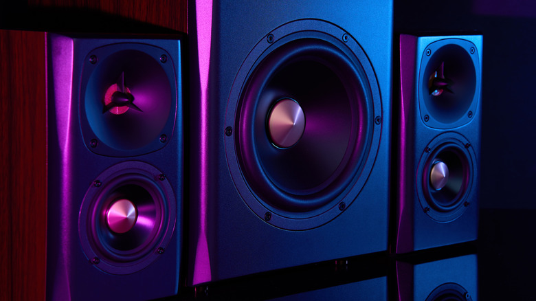 Close up of surround audio speakers, left, right, and subwoofer, with a purple glow