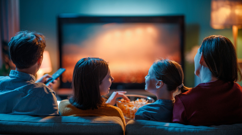 A family gathered around a TV in a living room.