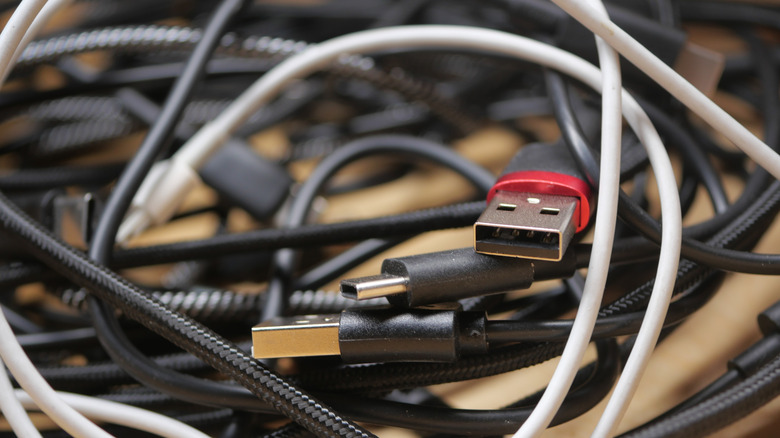 An assortment of tangled black and white USB cables