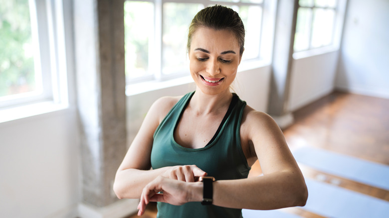 A woman in workout clothes checking her smartwatch
